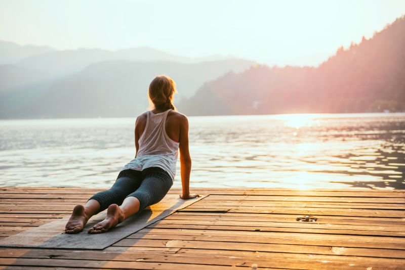 Women doing Sun Salutations near water To Activate Solar Plexus Chakra